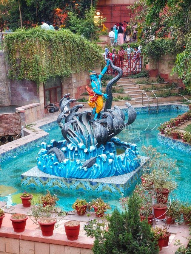Vibrant statue surrounded by water and greenery in an outdoor garden.